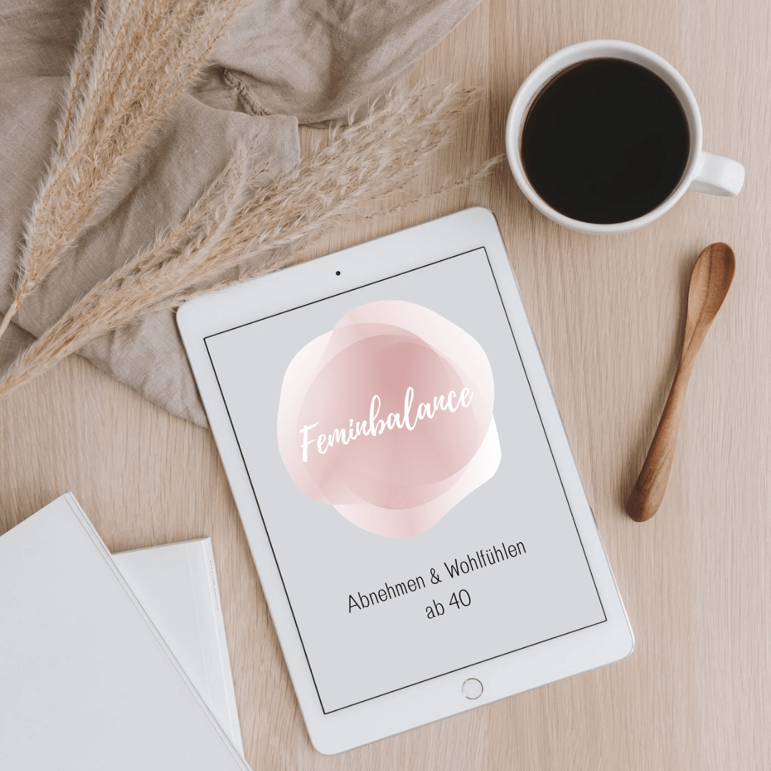 Tablet mit Feminbalance-Logo auf einem Holztisch neben Kaffeetasse